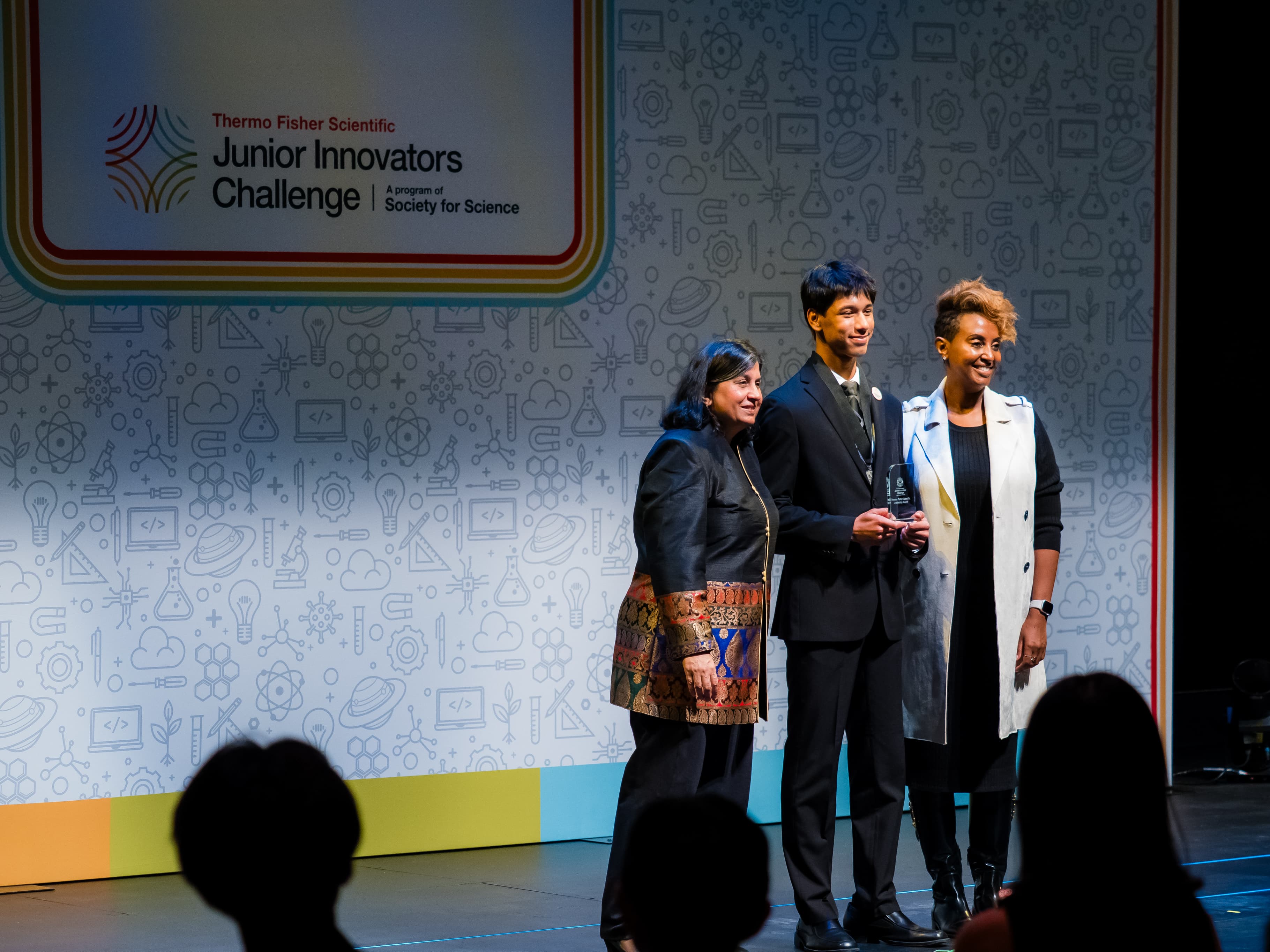 Akhil Nagori holding the Broadcom award on stage with presenters